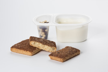 Yogurt with chocolate balls. Double plastic cup with white yogurt and sweet cinnamon cookies.