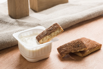 Children's white yoghurt in a plastic cup with sweet cookies
