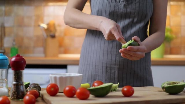 Woman making traditional Mexican sauce Guacamole from fresh ripe avocados.