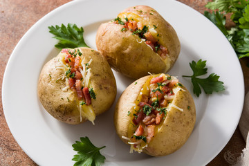 Stuffed potatoes with bacon and cheese on plate on rusty background