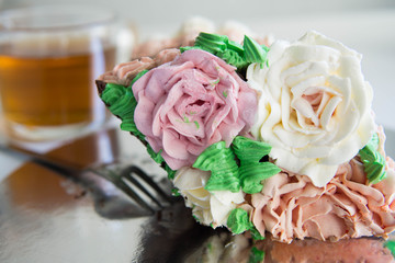 A piece of homemade chocolate cake with cream made flowers of soft colors pink and white.