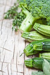 Variety of green organic vegetables on rustic wooden background.