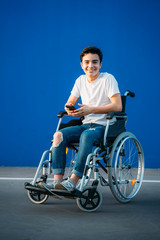 Obraz premium Portrait of young man on wheelchair using mobile phone