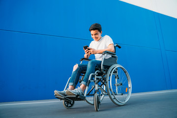 Portrait of young man on wheelchair using mobile phone