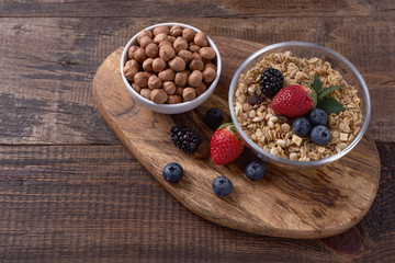 Granola with hazelnuts and berries on wooden background. Healthy breakfast.
