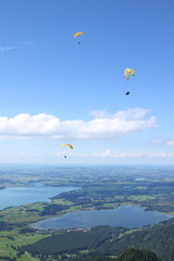Three paragliders over the Forggen and Bannwaldsee