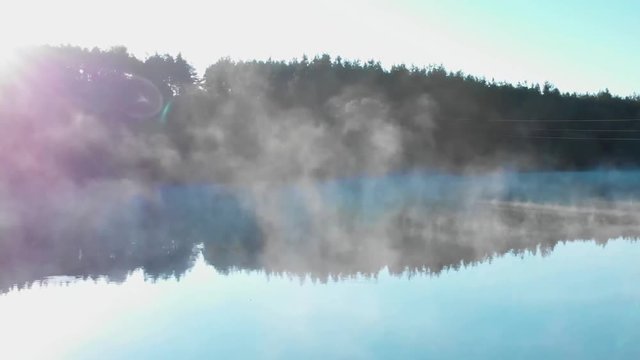 Sunrise over forest in front of foggy lake - panning shot, 59.94 fps