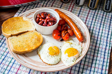 Traditional English Breakfast - Eggs, Sausage, Tomato, Toasts, Beans