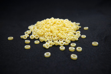 Pasta noodles small ring of raw on a black background.