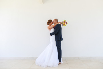 Beautiful wedding couple posing in front of white wall