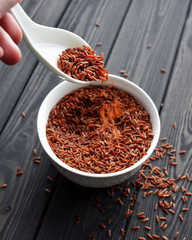 hand holdind a spoon with red rice pouring