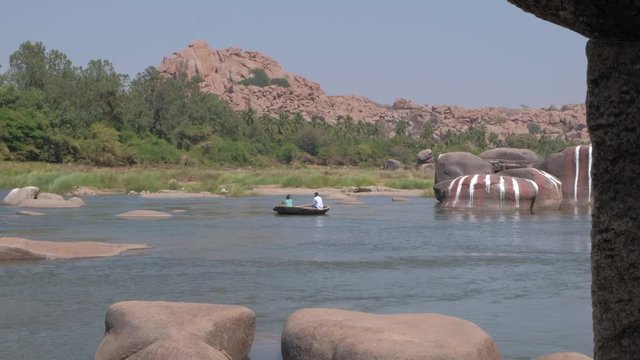 View of the River Tungabhadra in Hampi, capital of the Vijayanagara empire, sits on the banks of the Tungabhadra River with boat for transportation and warning to not swim in the river 