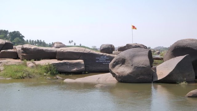 View of the River Tungabhadra in Hampi, capital of the Vijayanagara empire, sits on the banks of the Tungabhadra River with boat for transportation and warning to not swim in the river 