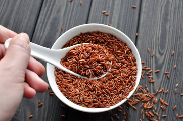 hand holdind a spoon with uncooked red rice