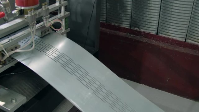 Closeup shot of a length of steel being stamped and having a pattern cut into the aluminium sheet