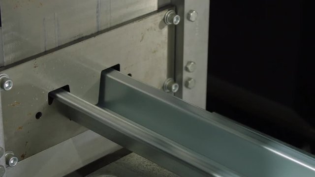 Closeup of a fabricated length of steel being cut with a guillotine in manufacturing