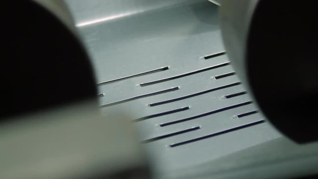 Extreme closeup of rollers of a automated machine feeding steel in the stamping process of manufacture cable tray