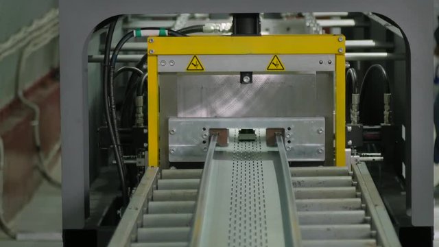 A fabricated length of steel for cable tray is fed out of a automated machine which stamps the part
