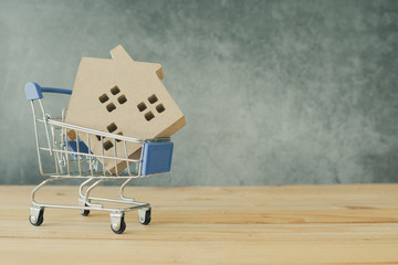 real estate and buying and selling home concept, house model in cart on wooden table