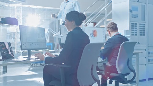 Back View of Team of Technology Engineers Working on Desktop Computers in Bright Office. Screens Show IDE / CAD Software, Implementation of Machine Learning, Neural Networking and Cloud Computing