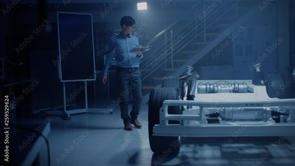Poster asian automobile engineer working on electric car chassis platform, using tablet computer with 3d ca