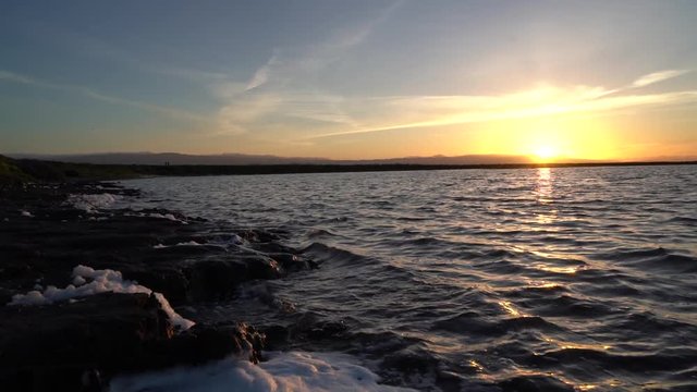 The sun setting below the horizon of a large salt pond at Alviso Marina County Park in Mountain View, California.