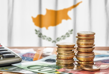 Geldscheine und Münzen vor der Nationalflagge Zyperns