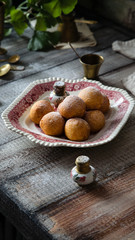 Homemade small round ball donuts sprinkled with powdered sugar on vintage plate