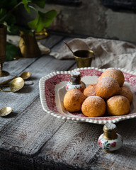 Homemade small round ball donuts sprinkled with powdered sugar on vintage plate