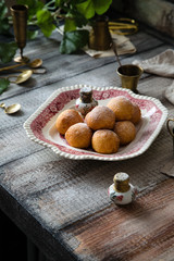 Homemade small round ball donuts sprinkled with powdered sugar on vintage plate