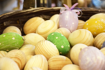 Many unpainting and colorful wooden eggs in a basket with selective focus. Wooden eggs, blanks for dyeing eggs. Wooden egg shape on the stand for painting. Easter egg, pysanka.