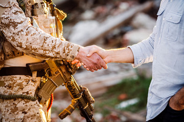 Soldier and civilian shaking hands on outdoor background