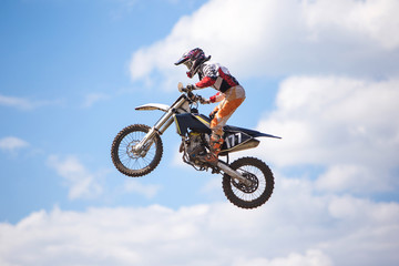 Fototapeta na wymiar Racer jumping against the blue sky on a motocross championship