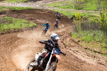 racers chase each other on a race track in motocross championship