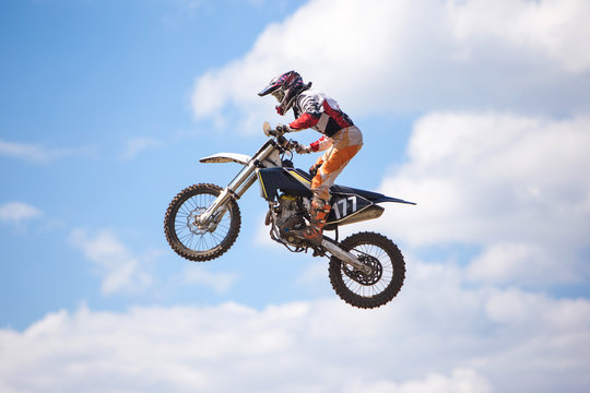 Racer jumping against the blue sky on a motocross championship