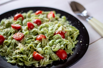 Green pasta with tomatoes and parmesan cheese. White background.
