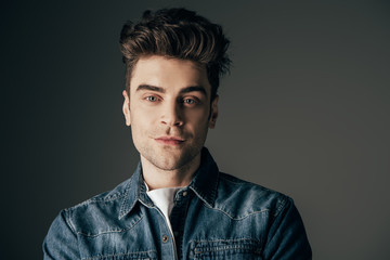 handsome and brunette man looking at camera isolated on black