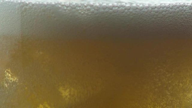 Close up of a golden hops fizzy drink being poured into a glass with ice.