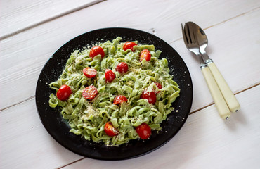 Green pasta with tomatoes and parmesan cheese. White background. Top view.