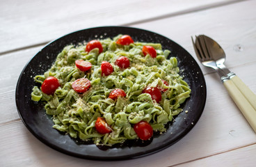 Green pasta with tomatoes and parmesan cheese. Top view.