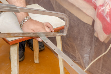 The use of a hacksaw blade and frame for cutting the metal construction for a stretch ceiling.