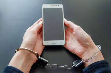 Arrested woman in handcuffs while holding the smart phone