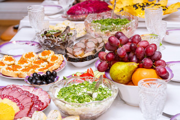 Snacks, fruits, sandwiches, salads, caviar and slicing on the holiday table