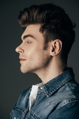 Obraz premium side view of handsome and brunette man in denim shirt isolated on black