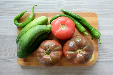 Vegetables on cutting board, tomatoes, cucumbers, peppers