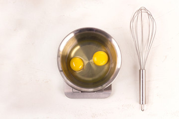 Separated egg whites and yolks in an iron kitchen bowl for beating. The Corolla. Flat lay.