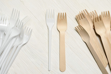 Disposable tableware from natural materials, wooden spoon, fork, knife, environmentally friendly. Comparison of plastic and wooden utensils. Place for text 