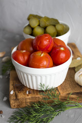 Marinated tomatoes with garlic, dill and spices in a plate on a gray background