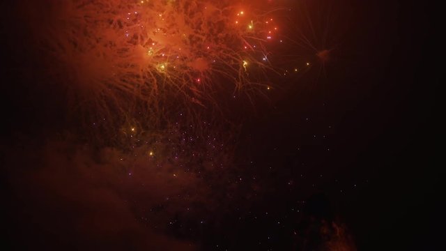 Beautiful 4k view of brightly colored fireworks exploding in the night sky. A young girl runs to look up at the amazing display.