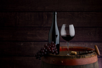 red wine bottle and wine glass on wodden barrel